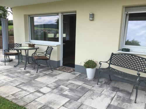 eine Terrasse mit zwei Bänken, einem Tisch und einem Fenster in der Unterkunft Ferienwohnung Am Galgenberg in Michelstadt