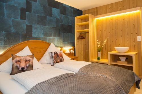 a bed with a dog and a cat sitting on it at Hostellerie Les Bagenelles in Sainte-Marie-aux-Mines