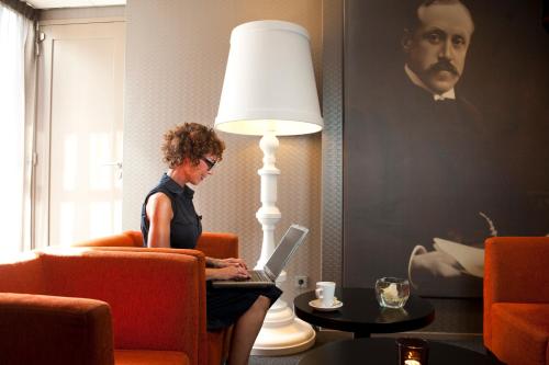 a woman sitting in a chair with a laptop at Hotel Ernst Sillem Hoeve in Den Dolder