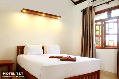 sypialnia z łóżkiem z białą pościelą i oknem w obiekcie Hotel T & T w mieście Anuradhapura
