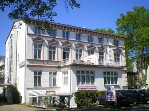 a large white building with a car parked in front of it at Haus Troja in Warnemünde