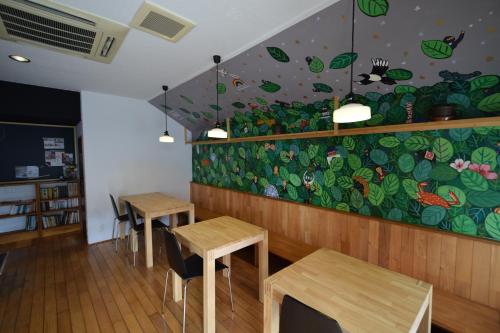 a restaurant with two tables and a colorful wall at Saga International Guesthouse Hagakure in Saga