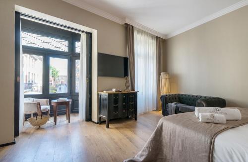 a hotel room with a bed and a couch and a television at Hotel Casa Peya - Adults Only in Palafrugell