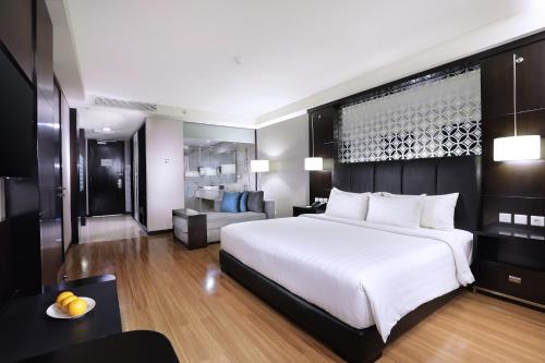 a bedroom with a large white bed and a couch at The Alana Hotel & Convention Center Solo by ASTON in Solo