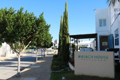a sign for a beach house restaurant next to trees at Apartment Caesar Beach in Kalecik