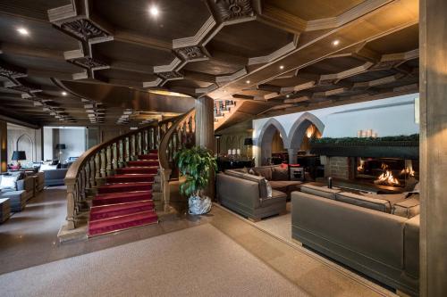 a lobby with couches and a staircase with a fireplace at Hotel Aaritz in Selva di Val Gardena