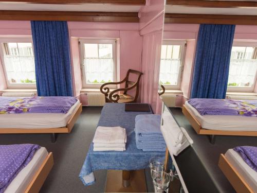 a room with two beds and a table and two windows at Gasthaus Pension zum Turm in Hospental