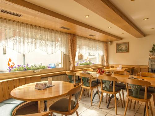ein Restaurant mit Holztischen und -stühlen und einem Fenster in der Unterkunft Gasthaus Pension zum Turm in Hospental