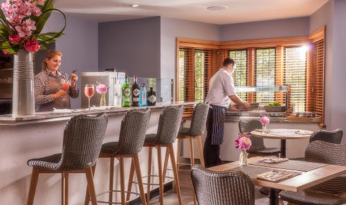 two people standing at a bar in a restaurant at Mallory Court Country House Hotel & Spa in Leamington Spa