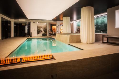 a swimming pool with a fireplace in a house at Hotel San Giacomo Spa&Gourmet in Brentonico