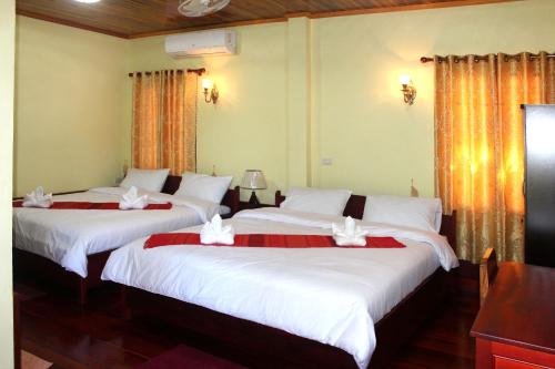 two beds in a hotel room with white sheets at Phonepraseuth Guesthouse in Luang Prabang