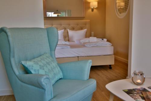 a bedroom with a bed and a blue chair at SATAMA Sauna Resort & SPA in Wendisch Rietz