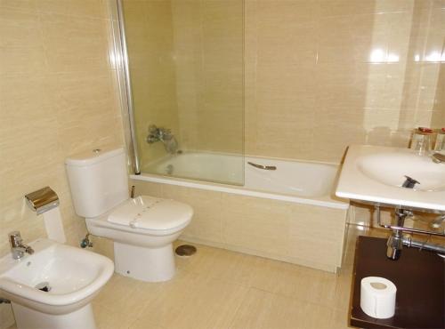a bathroom with a toilet and a tub and a sink at Hotel Millan in Negreira