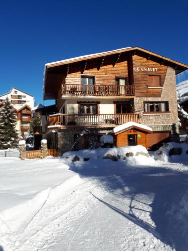 duży drewniany budynek z śniegiem przed nim w obiekcie Le Chalet w mieście Les Deux Alpes