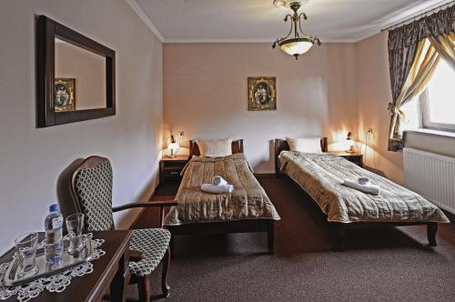 a bedroom with two beds and a table and chairs at Hotel & Restauracja Stylowa in Namysłów
