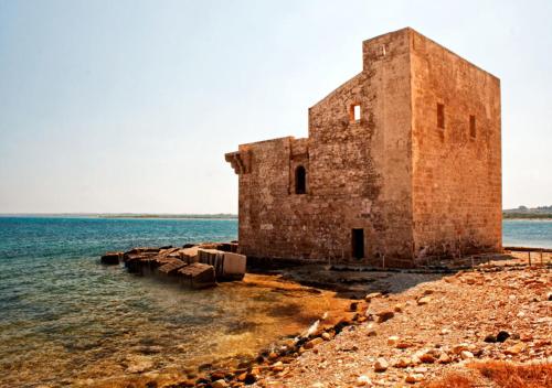 an old brick building on the shore of the water at Yachting Apartment in Marzamemi