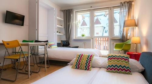 ザコパネにあるW Rent like home - Za Cieszynianką 4のベッド2台、テーブルと椅子が備わるホテルルームです。
