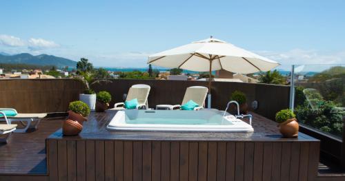 a hot tub on a patio with chairs and an umbrella at La Plage Residence in Garopaba
