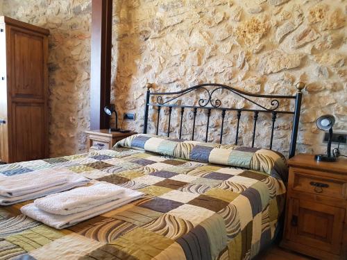 Cama en habitación con pared de piedra en Casa Rural Cal Puyo en Paúls