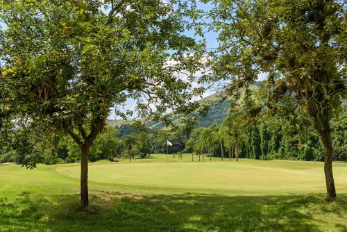 a view of a golf course with trees in the foreground at Hotel Fasano Angra dos Reis in Angra dos Reis