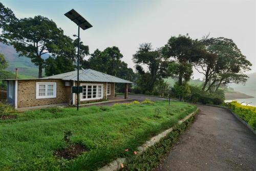 a small house with a street light next to a road at Manalar in Gūdalūr