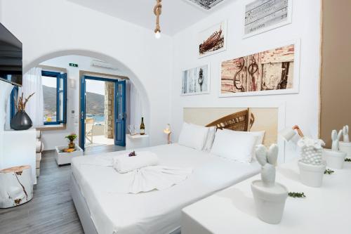 a white bedroom with a large white bed in a room at Kaerati Apartments in Katapola