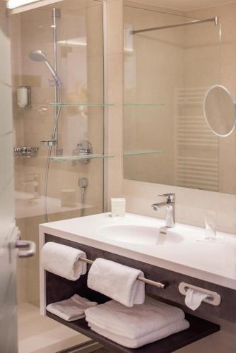 a bathroom with a sink and a shower with towels at DAS VIER Sport,- und Wellnesshotel in Sankt Leonhard im Pitztal