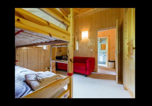 a bedroom with a bunk bed and a red couch at Chalet Clochette 4 Valles-Verbier in La Tzoumaz