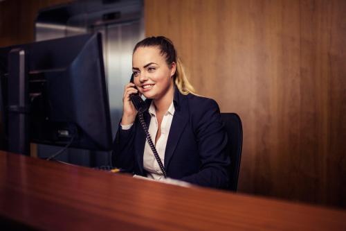 a woman sitting at a desk talking on a cell phone at Delta Hotel in Vlaardingen