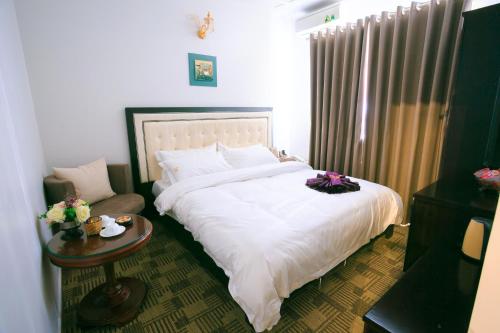 a bedroom with a large white bed and a table at Pham Ha Hotel in Hai Phong