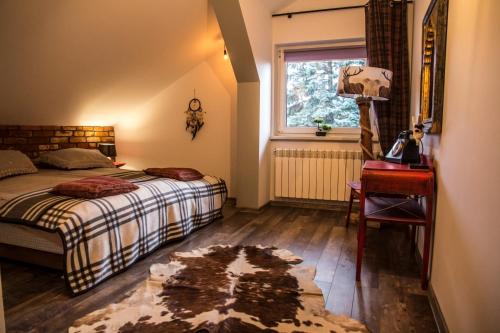 a bedroom with a bed and a desk and a window at Apartamenty Pan Tadeusz Ustroń in Ustroń