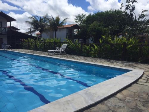 a swimming pool with a chair in front of a house at Casa de Luxo com 3 Suites no Condominio Horizonte da Serra 1 em Gravatá in Gravatá