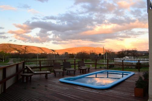 a hot tub on a deck with benches and a sunset at La Casa Grande in Sierra de la Ventana