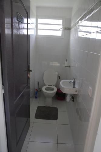 a white bathroom with a toilet and a sink at Chez Roberto Bungalow Ayden in Petit-Canal