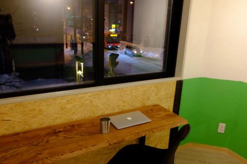 a laptop sitting on a wooden bench under a window at Asahikawa Ride in Asahikawa