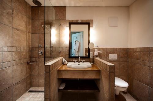 a bathroom with a sink and a toilet and a mirror at Gerber Park Hotel in Uhingen