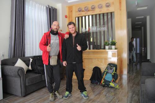 two men standing in a living room giving thumbs up at Maxim Hotel in Da Lat