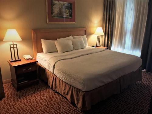 a large bed in a hotel room with two lamps at Host Inn an All Suites Hotel in Wilkes-Barre