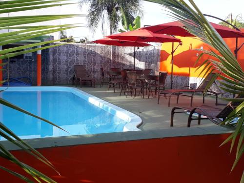 a swimming pool with umbrellas and tables and chairs at Pousada Sol Nascente in Olímpia