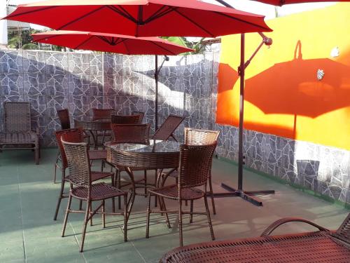 a table and chairs with red umbrellas on a patio at Pousada Sol Nascente in Olímpia