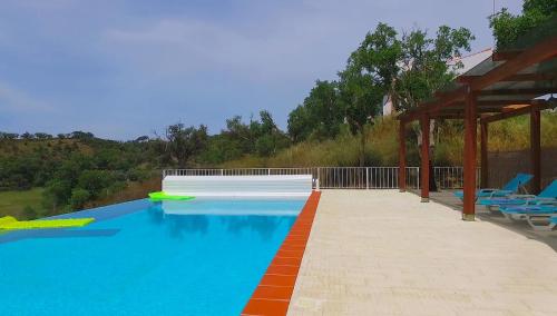 a large swimming pool with chairs and a pavilion at Monte da Ameira in Roncão