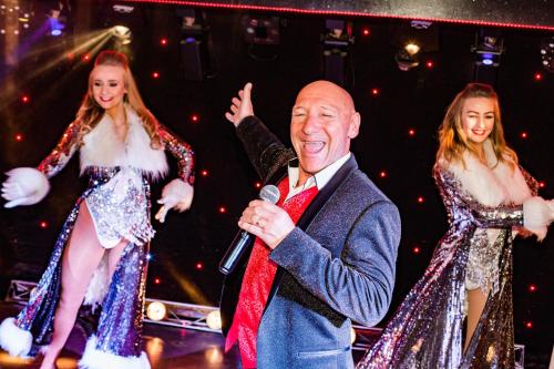a man singing into a microphone in front of two women at Viking Hotel - Adults Only in Blackpool