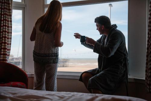 a man looking out a window at a woman at Viking Hotel - Adults Only in Blackpool