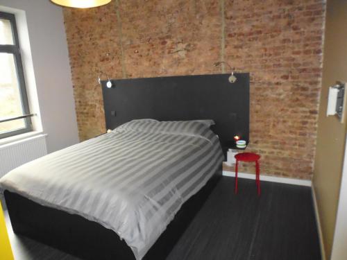 een bed in een kamer met een bakstenen muur bij Gîte Les 4 Vins in Longlier