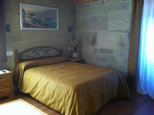 a bedroom with a bed with a yellow bedspread at As Chivas in Redondela