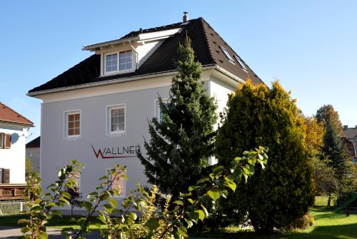 a white house with a black roof at Wallner - Hotel & Wirt in Arnoldstein