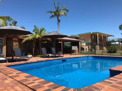 诺斯黑文Haven Waters Motel & Apartments的配有椅子和遮阳伞的游泳池