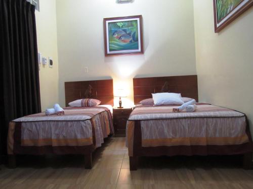 a hotel room with two beds and a lamp at Alojamiento El Cardenal in Iquitos