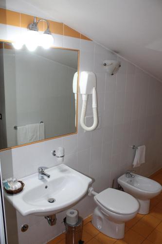 a bathroom with a sink and a toilet and a mirror at Hotel Vitti in Borghesiana 