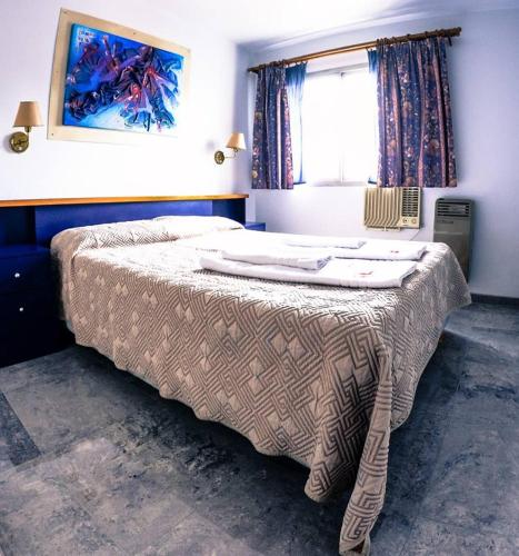a bedroom with a bed with a blanket on it at Apart Hotel Magali in Córdoba